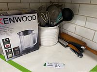 Photo showing Kenwood glass blender box, various cooking utensils in a white container, including a Wüsthof chef's cutting knife and other tools on a kitchen counter surface.