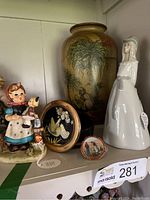 Shelf display of a crackle glaze vase, reproduction Hummel girl figurine, Spanish porcelain lady figurine, round trinket box, and small Limoges plate.