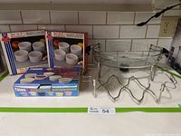 Photo showing two boxed sets of 4 white ceramic ramekins each, and two clear glass bakeware dishes with metal holders