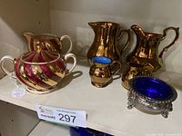 Photo showing the various creamers and sugar set, copper-tone pitchers, and the sterling salt cellar with blue insert.