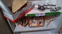 Photo shows vintage metal cookie press with attachments, metal and plastic icing bags, and various metal cookie cutters on shelves.