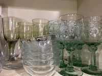 Photo showing three different types of glasses and six clear bowls arranged on a shelf