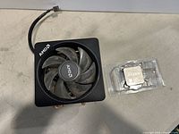 AMD Ryzen 7 3700X processor and AMD Wraith Prism LED cooler shown from above, cooler fan visible with AMD logo, processor in plastic clamshell.