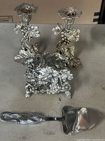 Three grapevine pattern candlesticks with detailed grape and leaf designs, tarnished silver plating