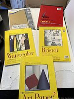 Five assorted art paper pads on table: Mead tracing paper, Mead paint pad, Strathmore watercolor, Strathmore bristol, and Strathmore drawing pads.