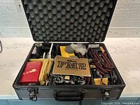 Opened hard-shell case showing camera body, lenses, flashes, meter, tubes, filters