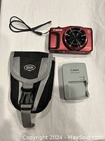 Camera, charger, and carrying case displayed together on white background