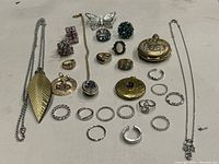Full display of all costume jewelry pieces including rings, pendants, necklaces, brooch, and pocket watch pendant.