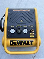 Front view showing pressure gauges, regulator knob, connection fitting, and Dewalt logo.