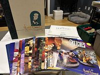 18 issues of Walt Disney Collectors Society Sketches magazines laid out in a row with the bonus Lion King art print set and storage box behind them.