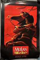 Photo of front side of Mulan 1998 movie poster in red and black with character profile and horse.