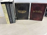 Photograph showing two Lord of the Rings DVD sets: The Fellowship of the Ring and The Two Towers, with slipcases visible next to three paperback books.