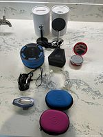 All items shown on countertop include Bluetooth speakers, earbuds with cases, and Oh Snap phone grip stands.