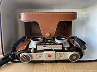 Front top view of Kodak Stereo Camera showing twin lenses and control dials with leather case rear flap open