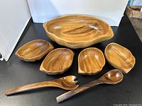 Full set of a large wooden salad bowl, four smaller wooden bowls, and wooden salad fork and spoon on display, showing overall appearance and size relationship.