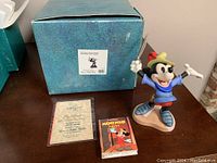 Full lot showing the Mickey Brave Little Tailor sculpture, two books, and original box on table.
