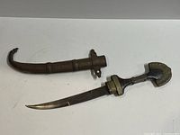 Dagger unsheathed showing curved blade, wooden handle, and metal guard.