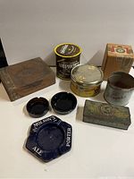 Lot of vintage tobacco-related collectibles grouped: wooden cigar box, multiple cigarette tins, and three ashtrays including Molson's Ale porter ashtray