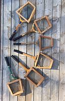 Top view of six wooden racquets arranged with their respective wooden square and trapezoidal-shaped presses on a wooden deck surface.