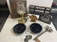 Full view of lot showing various items including wooden box, oil lamp, abacus, clock, ashtrays, carved fish, key, and candle holder figurine.