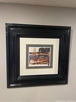 Full view of framed print The Canoe by Tom Thomson hung on a wall