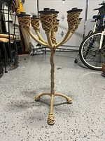 Full view of 7-candle holder wrapped in rope, standing on a speckled floor with surrounding garage items.