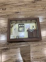 Framed 3D kitchen picture showing detailed miniatures like cabinet, shelves, apron, bottle, and bucket.