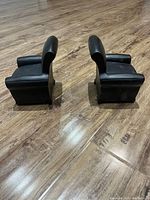 Photo showing the pair of black metal sofa-shaped book holders from the side, illustrating their design and size relative to the floor.