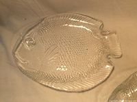 Single glass fish shaped serving dish showing texture and detailed features.