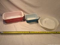 Three Pyrex baking dishes shown side by side with measuring tape for size reference.