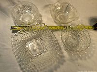 Top and angled views of 4 clear cut glass dishes showing varied geometric and floral cut designs and shapes.