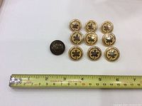 Top-down image showing 9 gold-tone Air Canada jacket buttons and 1 dark Canadian military button with measuring tape for scale.
