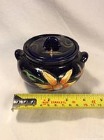 Front and side view of the deep blue ceramic notion bowl showing floral painted design and lid with knob handle.