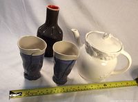 Photo showing the Japanese teapot, two signed KAI cups, and Italian vase together with measuring tape
