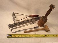 Full set of kitchen utensils including chocolate mold, two wooden mallets, potato masher and tongs with measuring tape for scale