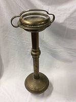 Full view showing the tall brass pedestal ashtray stand with stable base.