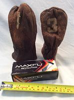 Two vintage brown leather golf wood club covers along with a box of Maxfli Revolution golf balls and a measuring tape for scale.