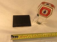 Molson Export draft tap handle and black 'Smokes' cigarette case with tape measure to show dimensions.
