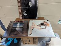 Photo showing three vinyl LP album covers, including Doobie Brothers, The Cars, and Don Henley, placed on a box.