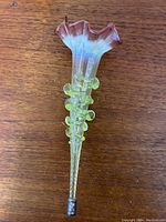 Art Nouveau cranberry and fluorescent vaseline glass epergne vase on wooden table, visible details of ruffled cranberry rim and yellow fluorescent body with applied glass knobs