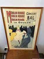 Front view of framed Moulin Rouge concert bal antique poster showing artwork and text with La Goulue dancing and man silhouette.