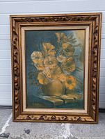 Frontal image of the signed impressionist floral oil painting in carved wooden frame, showing yellow flowers in vase on blue-green background.