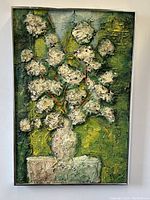 Frontal view of thick impasto floral painting signed by Millaces, showing textured white flowers, green background, and vase on table.
