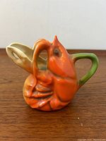 Front view of Royal Bayreuth lobster cream jug showing vibrant orange-red colors, lobster claw handle painted green and cream spout.