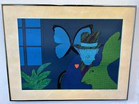 Full view of the framed serigraph artwork showing a blue-faced figure, butterfly wing, and green rabbit figure.