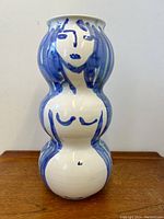 Front view of swollen double-bulb shaped pottery vase, white glazed with blue Picasso style female figure painting.