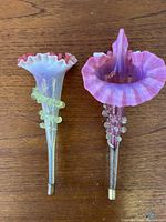 Pair of cranberry vaseline glass Art Nouveau epergne vases photographed on wood surface showing colors and ruffled edges.