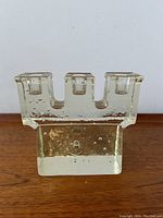 Front view showing three candle slots and bubble texture in the thick clear glass construction.