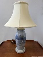 Full view of the vintage Bing & Grondahl porcelain table lamp with scenic landscape design, showing cream lampshade and painted porcelain base.
