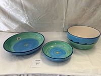 Three ceramic bowls with hand-painted ocean/starfish theme arranged on a white cloth.